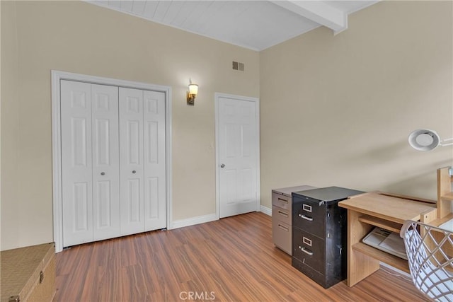 home office featuring baseboards, wood finished floors, visible vents, and beam ceiling