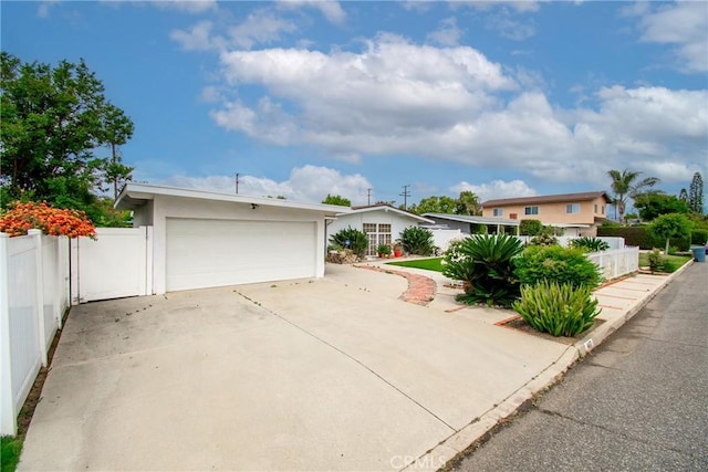 view of front facade featuring fence, stucco siding, driveway, and a garage