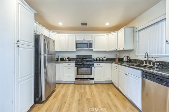 kitchen with stainless steel appliances, white cabinets, and light wood-type flooring