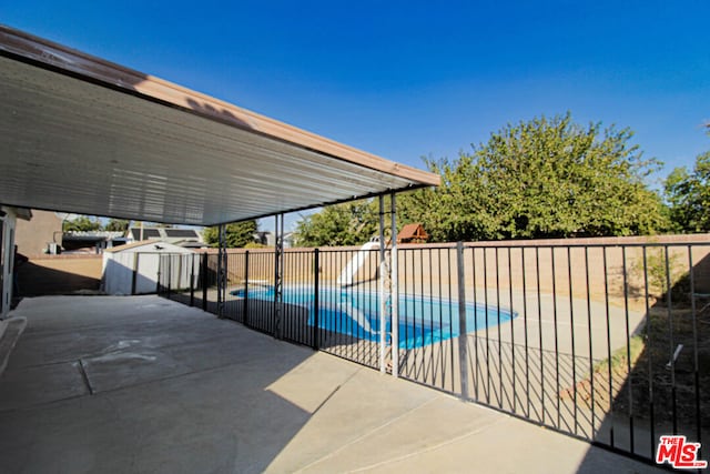 view of pool with a patio and a storage shed