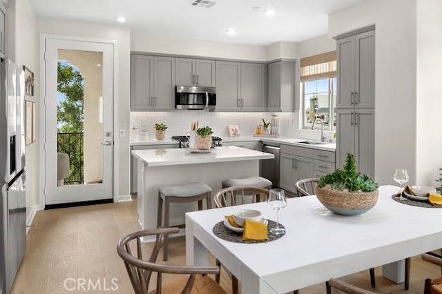 kitchen with a wealth of natural light, a center island, stainless steel appliances, and light hardwood / wood-style floors