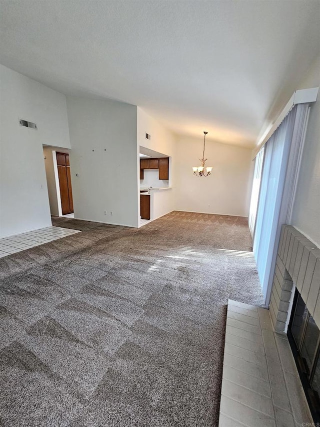 unfurnished living room featuring carpet floors, a fireplace, and an inviting chandelier