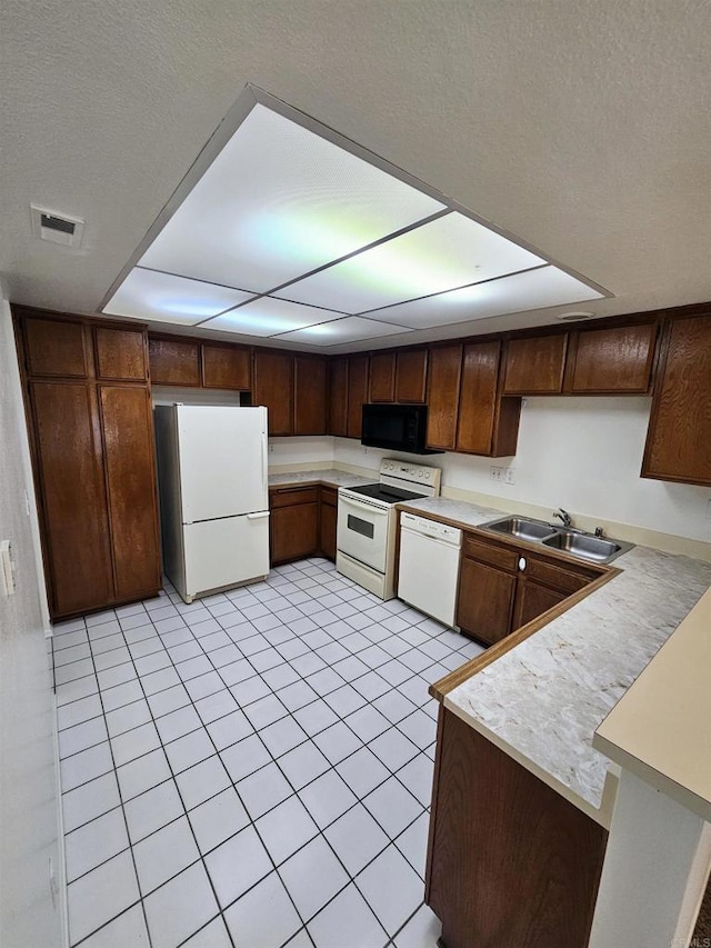 kitchen featuring light tile patterned floors, white appliances, dark brown cabinets, and sink