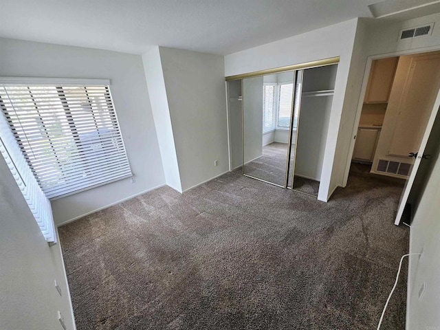 unfurnished bedroom featuring dark colored carpet and a closet