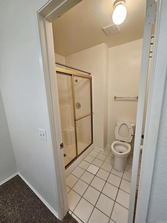 bathroom featuring toilet, tile patterned floors, and a shower with door