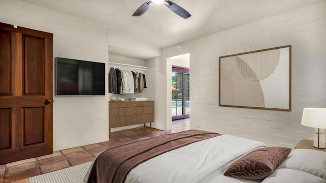 tiled bedroom featuring ceiling fan, a closet, brick wall, and lofted ceiling