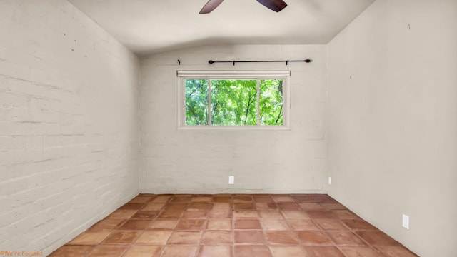 empty room with ceiling fan, lofted ceiling, and brick wall