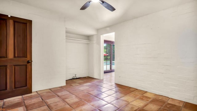 empty room with ceiling fan, brick wall, and vaulted ceiling