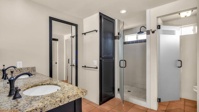 bathroom with tile patterned flooring, vanity, toilet, and walk in shower