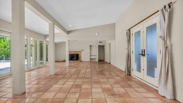 unfurnished living room featuring light tile patterned flooring, high vaulted ceiling, and french doors