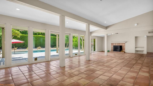 unfurnished living room featuring a fireplace, light tile patterned floors, and high vaulted ceiling