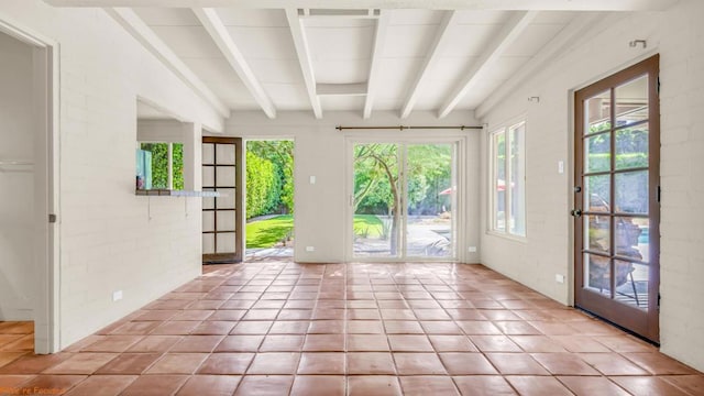 doorway with beam ceiling, light tile patterned flooring, and a healthy amount of sunlight