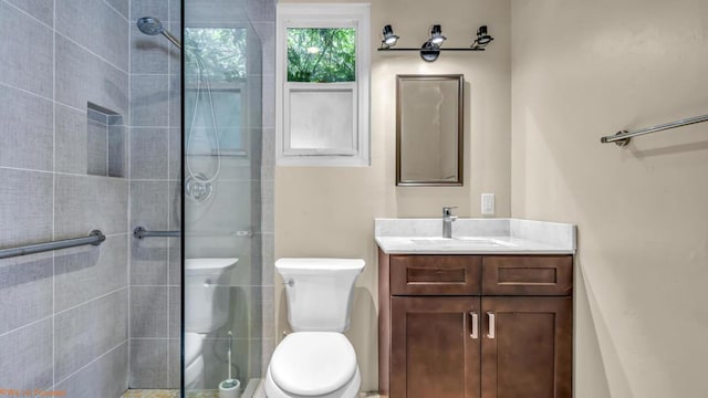 bathroom featuring a tile shower, vanity, and toilet