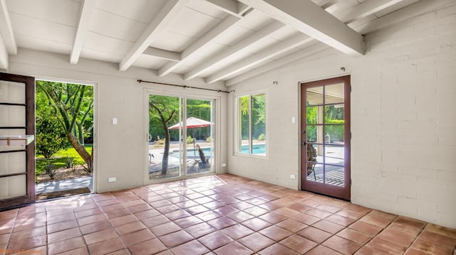 doorway featuring light tile patterned flooring, lofted ceiling with beams, and brick wall