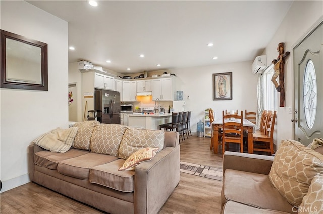 living room featuring light hardwood / wood-style floors, sink, and a wall mounted AC