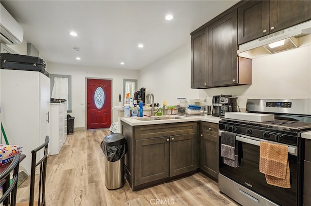 kitchen with dark brown cabinets, light hardwood / wood-style flooring, gas stove, and a wall mounted AC