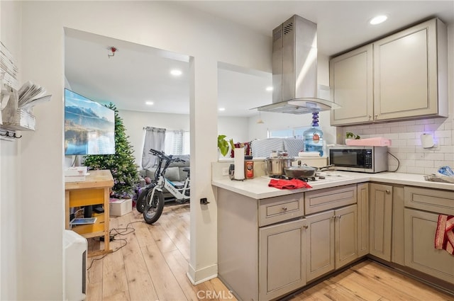 kitchen with light hardwood / wood-style flooring, wall chimney range hood, and decorative backsplash