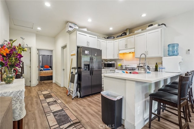 kitchen with stainless steel appliances, a breakfast bar, kitchen peninsula, and white cabinetry