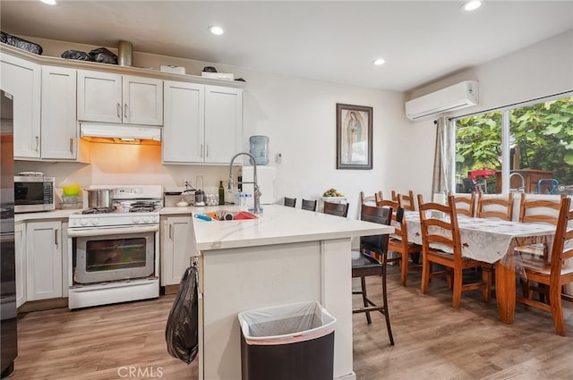 kitchen with light hardwood / wood-style flooring, white cabinetry, a wall unit AC, and white gas stove