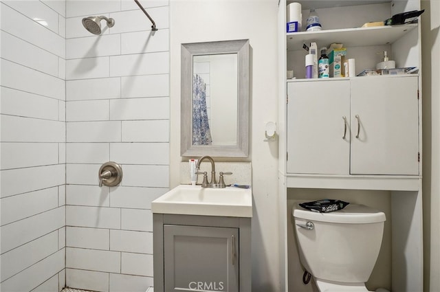 bathroom with a tile shower, vanity, and toilet