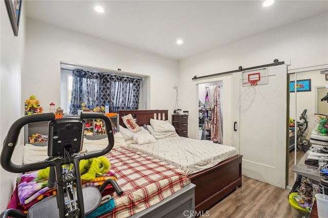 bedroom with light hardwood / wood-style flooring and a barn door