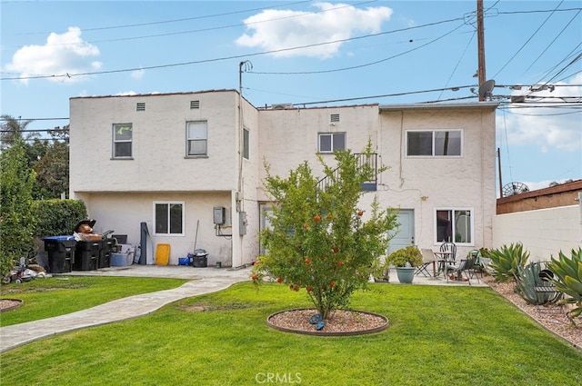 back of property with a yard and a patio