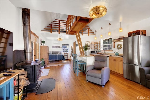 kitchen featuring stainless steel appliances, hanging light fixtures, light hardwood / wood-style flooring, and a wood stove