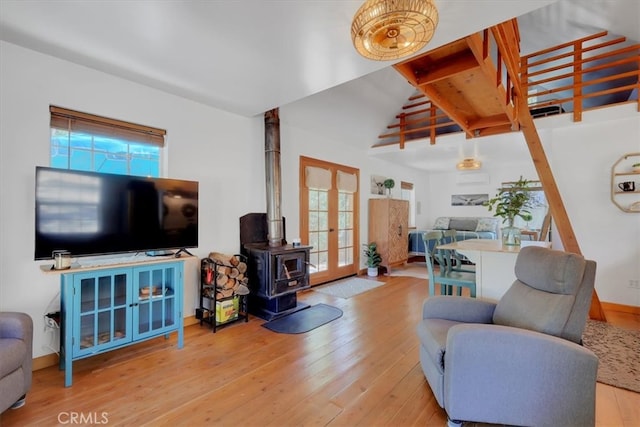 living room with french doors, lofted ceiling with beams, light hardwood / wood-style flooring, and a wood stove