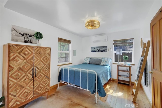 bedroom with an AC wall unit, hardwood / wood-style flooring, and multiple windows