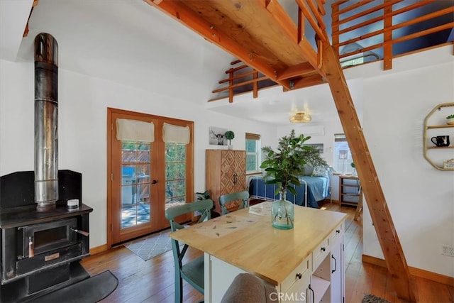 dining area featuring french doors, hardwood / wood-style flooring, beam ceiling, and a wood stove