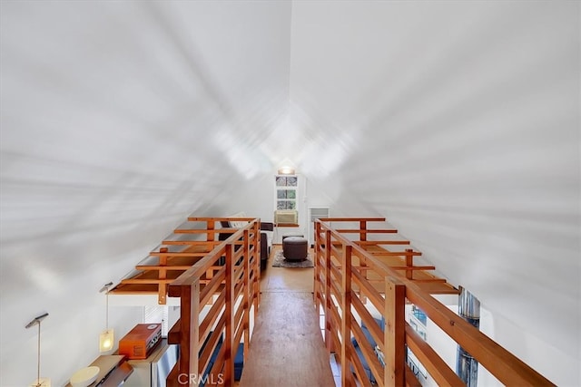 stairway with wood-type flooring and vaulted ceiling