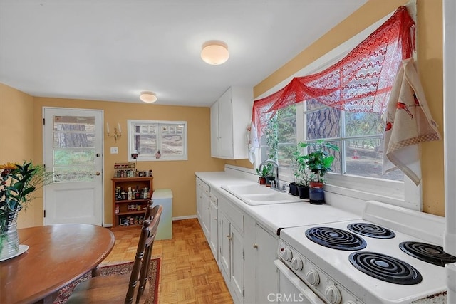 kitchen featuring white electric range, a wealth of natural light, and white cabinetry