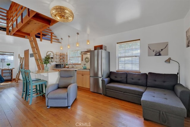 living room with light wood-type flooring, sink, and lofted ceiling