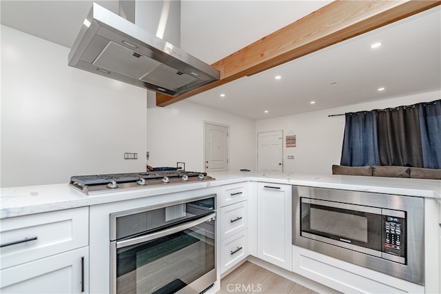 kitchen featuring appliances with stainless steel finishes, light hardwood / wood-style flooring, white cabinetry, and ventilation hood