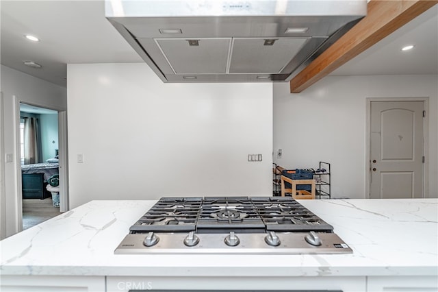 kitchen featuring stainless steel gas stovetop, light stone counters, and range hood