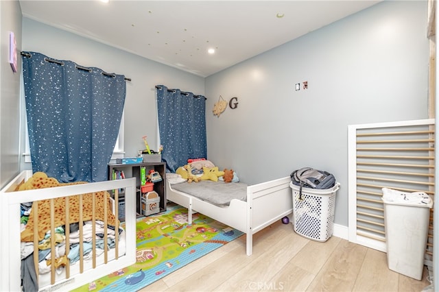 bedroom featuring a nursery area and wood-type flooring