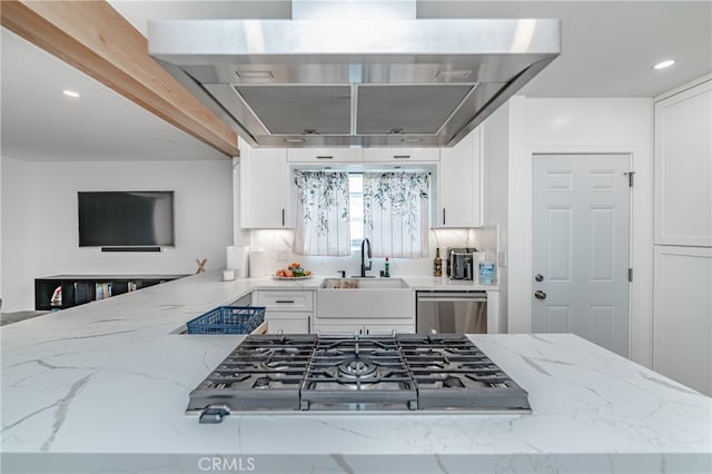 kitchen featuring tasteful backsplash, light stone countertops, appliances with stainless steel finishes, sink, and white cabinets