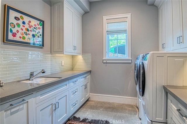 clothes washing area featuring cabinets, sink, and separate washer and dryer