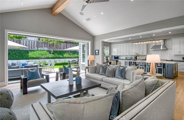 living room with ceiling fan, high vaulted ceiling, beamed ceiling, and light hardwood / wood-style flooring