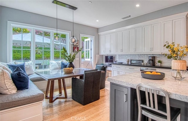 kitchen featuring decorative backsplash, white cabinets, and decorative light fixtures