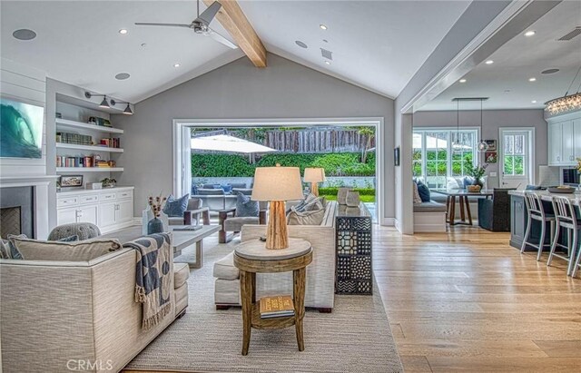 living room with ceiling fan, lofted ceiling with beams, built in features, and light hardwood / wood-style floors