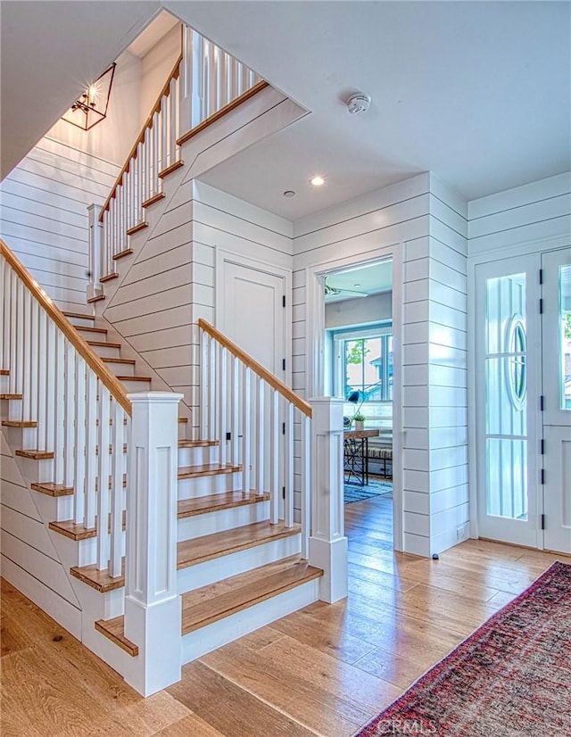 foyer entrance with wooden walls and light hardwood / wood-style floors