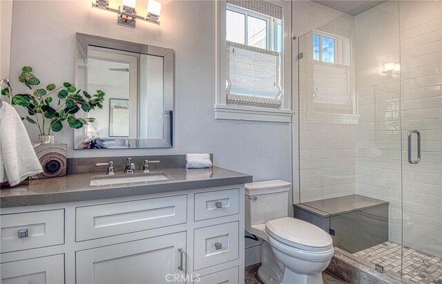 bathroom featuring an enclosed shower, vanity, and toilet