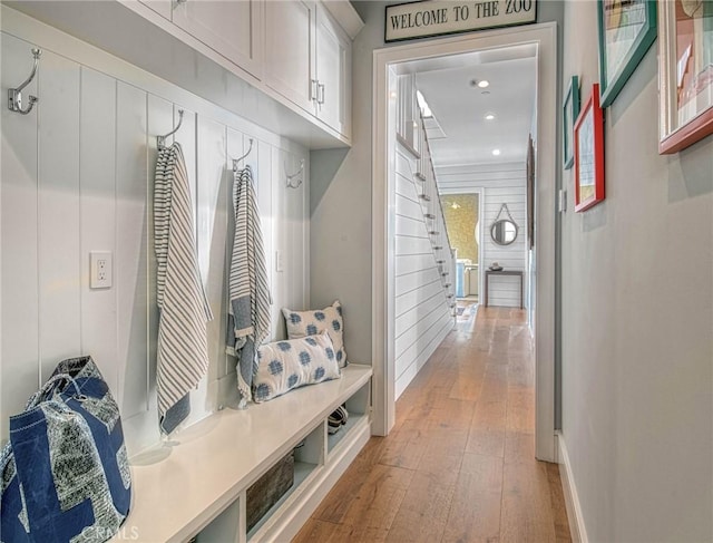 mudroom with wood walls and light hardwood / wood-style floors