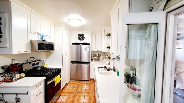 kitchen with sink, stainless steel appliances, white cabinets, and light tile patterned flooring