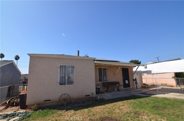 14407 S Corlett Ave, Compton, CA 90220 - rear view of house with a patio area, roof mounted solar panels, stucco siding, and crawl space