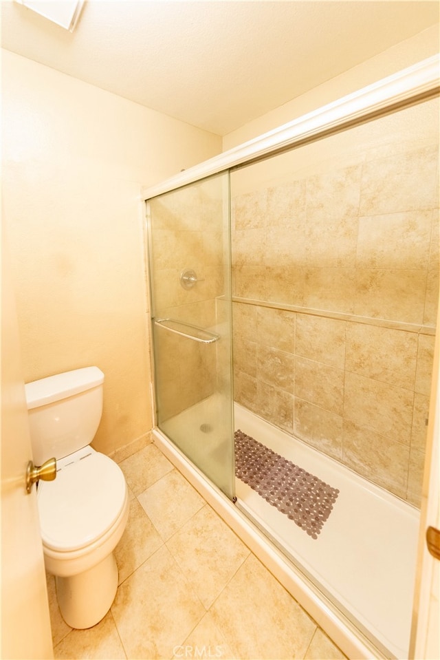 bathroom featuring walk in shower, toilet, and tile patterned floors