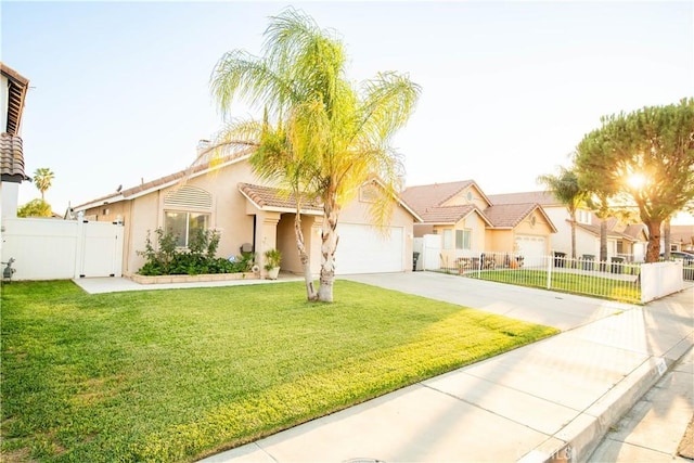 mediterranean / spanish-style house featuring a garage, concrete driveway, fence, a front yard, and stucco siding