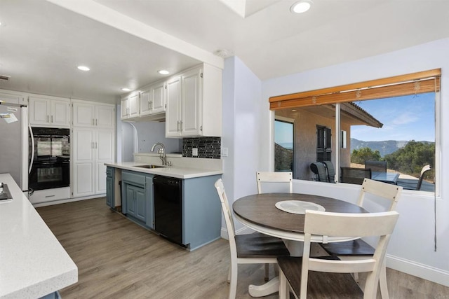 kitchen featuring sink, white cabinets, decorative backsplash, black appliances, and blue cabinetry