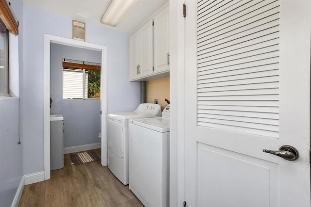 clothes washing area with cabinets, wood-type flooring, and washer and clothes dryer